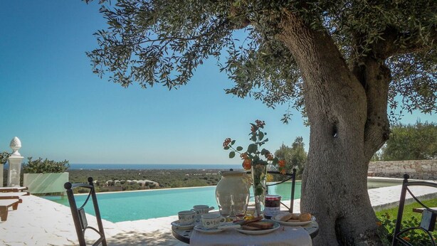 Une table dressée à l’extérieur, avec vue sur une piscine et un paysage.