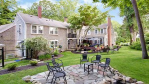 A two-story house with a patio area featuring stone flooring and outdoor furniture.