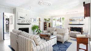 A living room with striped sofas, a fireplace, and a bookshelf.