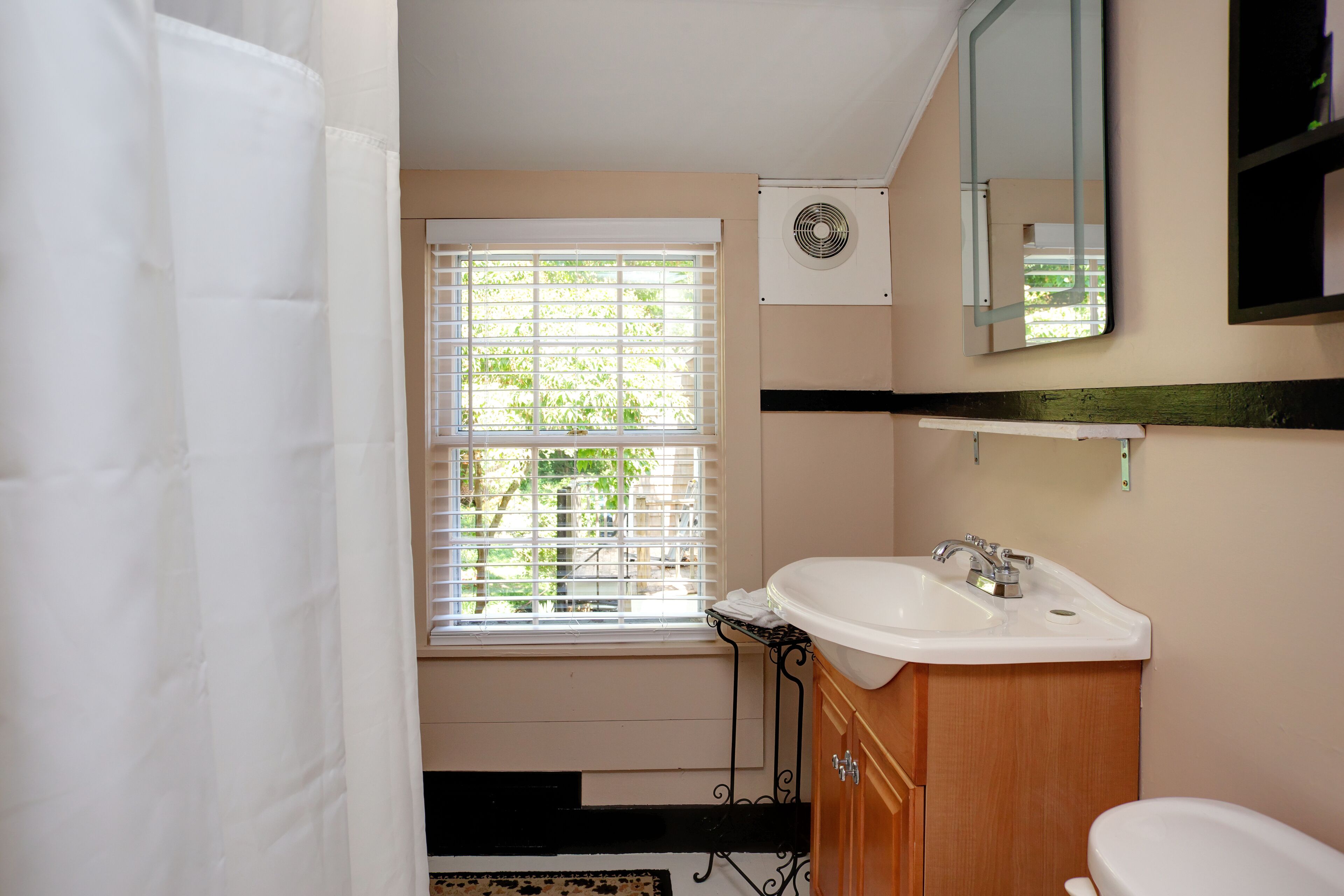 Une salle de bain avec une fenêtre, un lavabo, des toilettes et un miroir.