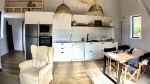A modern kitchen with white cabinetry, a built-in oven, and a dining area with a wooden table and chairs.
