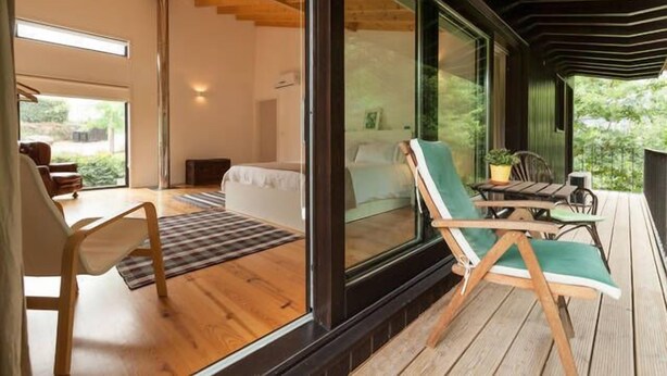 A modern room with a large glass window, wooden flooring, and a cozy seating area with a table and chairs.