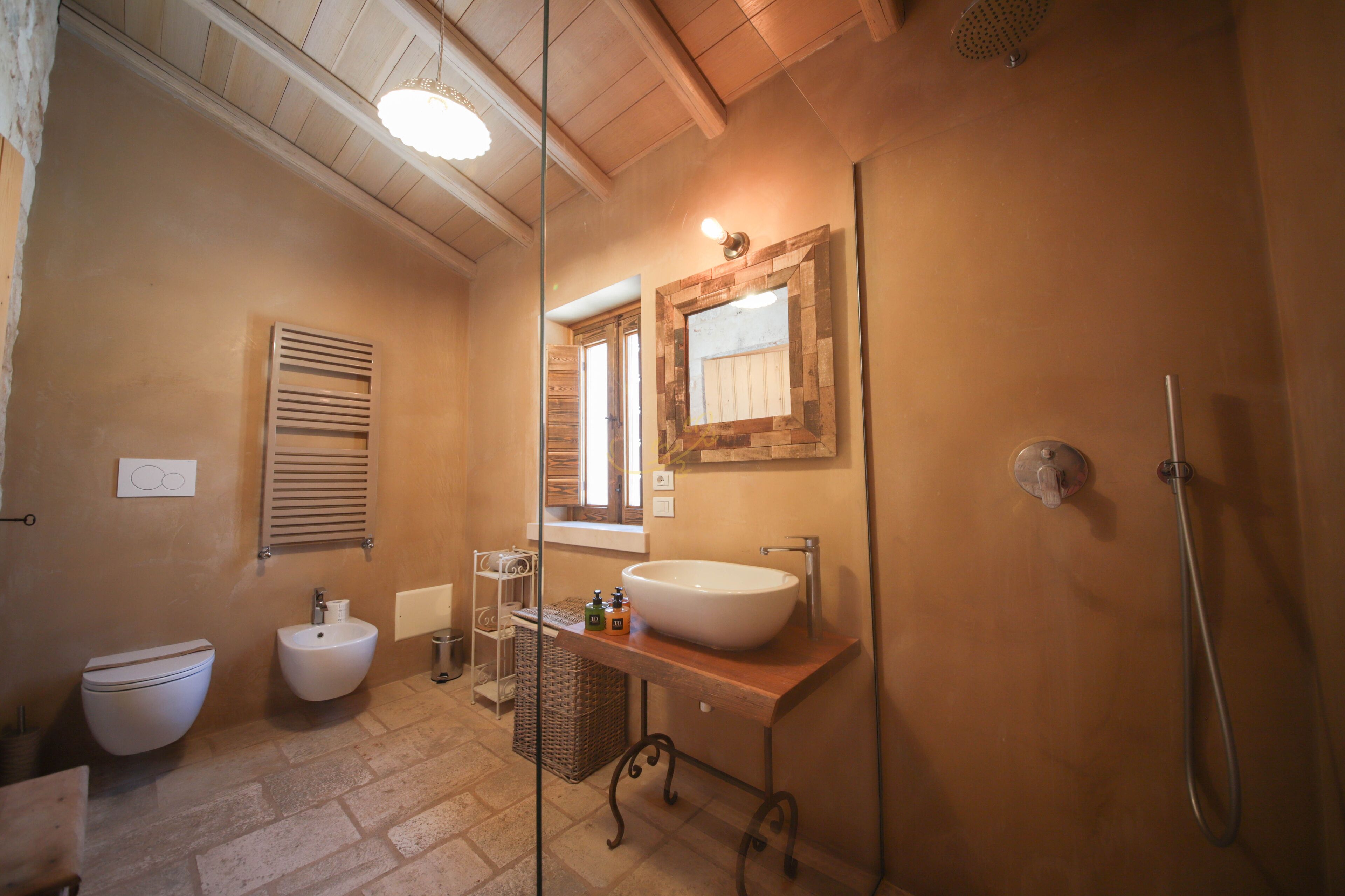 A bathroom with a white sink, a bidet, and a shower.