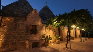 A stone building with conical roofs and potted plants. - TD Trulli di Montaltino with Stunning Huge Pool (Polignano a Mare)
