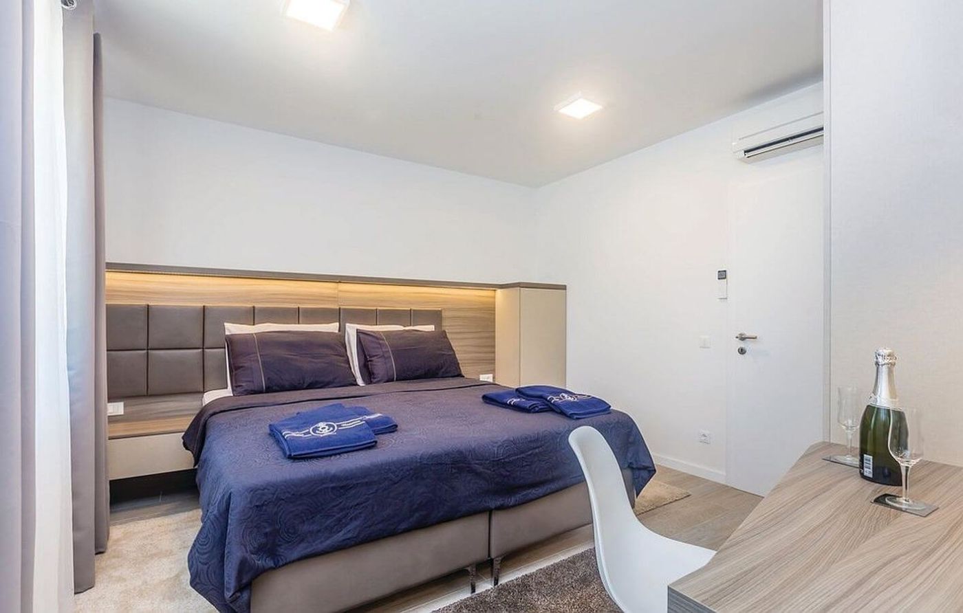 A modern hotel room with a bed, a desk, and a chair.