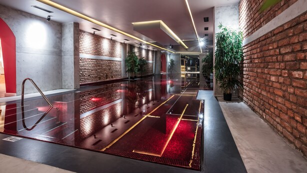 A modern indoor space with a polished floor, brick walls, and ceiling lights. - Next Door Park (Skopje)