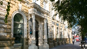 Un edificio storico con architettura classica, caratterizzato da finestre ad arco e colonne, con una segnaletica che indica che si tratta di un hotel.