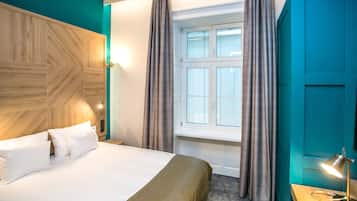 Ein Hotelzimmer mit Bett, Vorhängen, Fenster und Lampe.