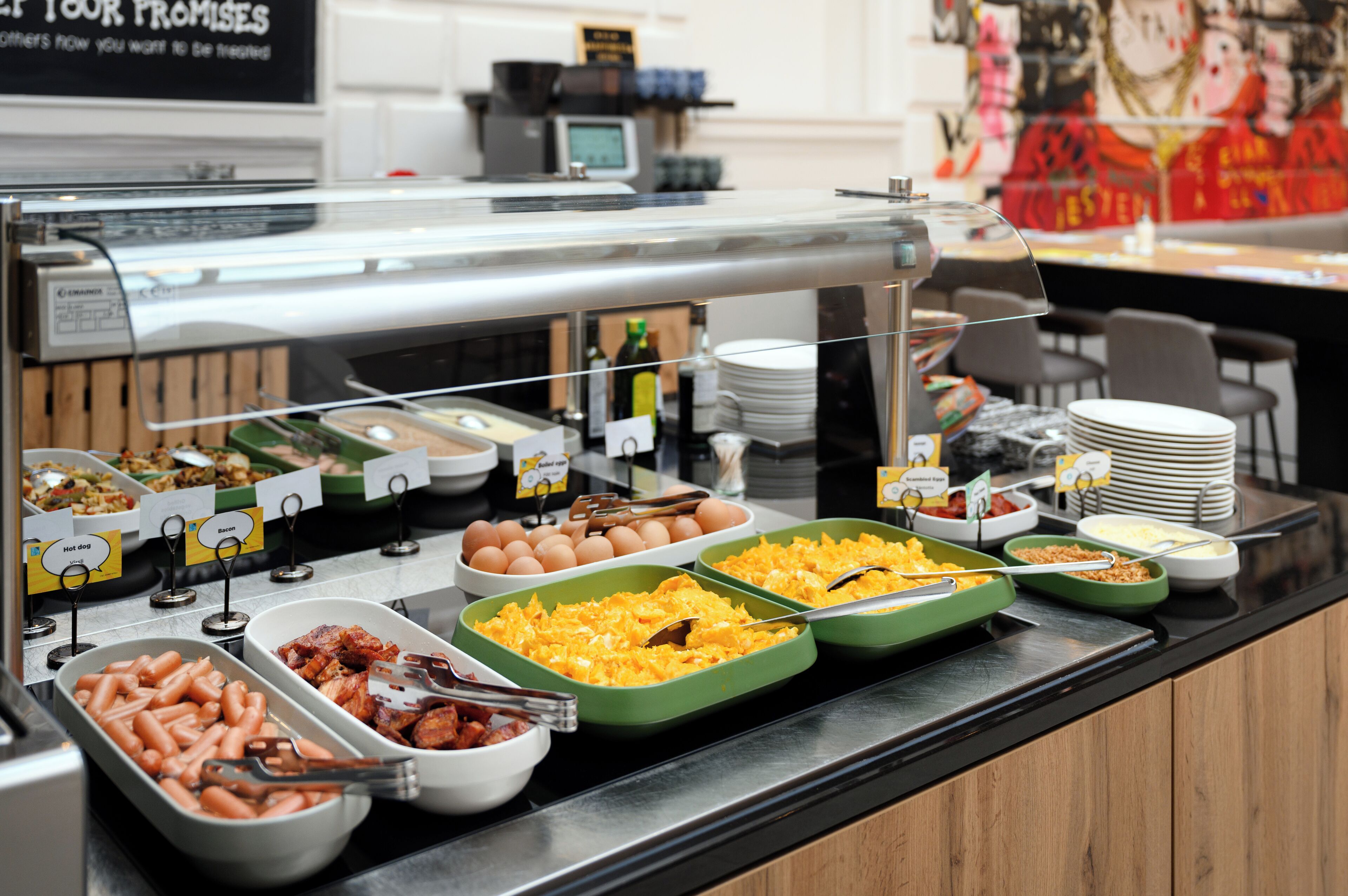 Een buffet met diverse gerechtjes, waaronder hotdogs, eieren en macaroni met kaas.