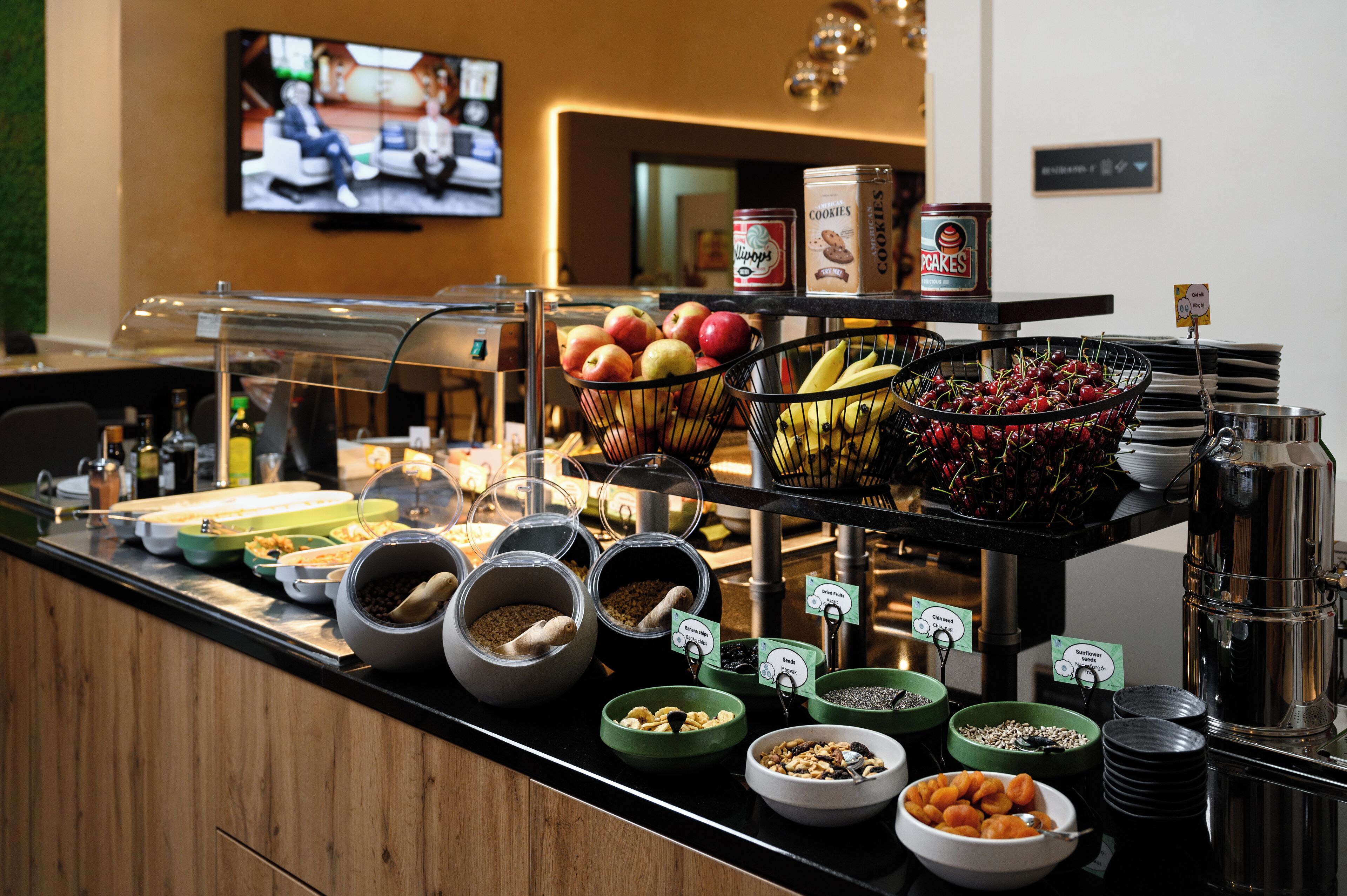Un buffet proposant une variété de plats, avec un téléviseur allumé en arrière-plan.