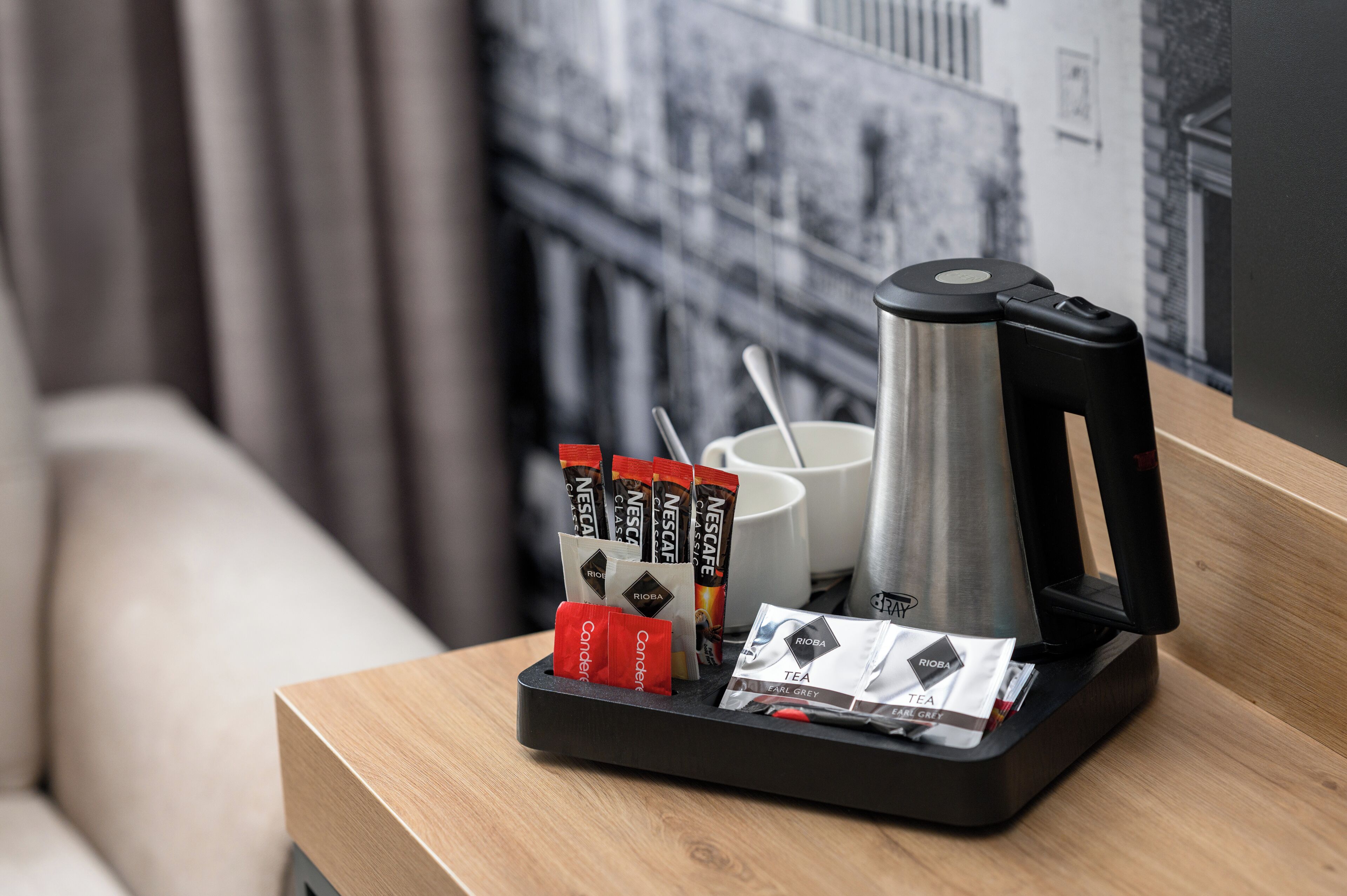 Eine Kaffeemaschine, eine Tasse und Teebeutel auf einem Holztisch.