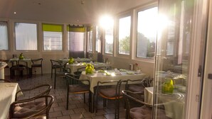 Un espace repas avec des tables dressées pour les repas, des chaises et une fenêtre donnant sur un paysage agréable.