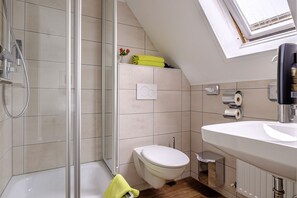 A modern bathroom with a shower, toilet, and sink. - Also-hotel an der Hardt (Wuppertal)