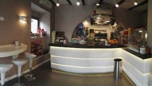 A modern bar area with a curved counter, white bar stools, and a visible trash bin. - Hotel Residence Risorgimento (Vibo Valentia)