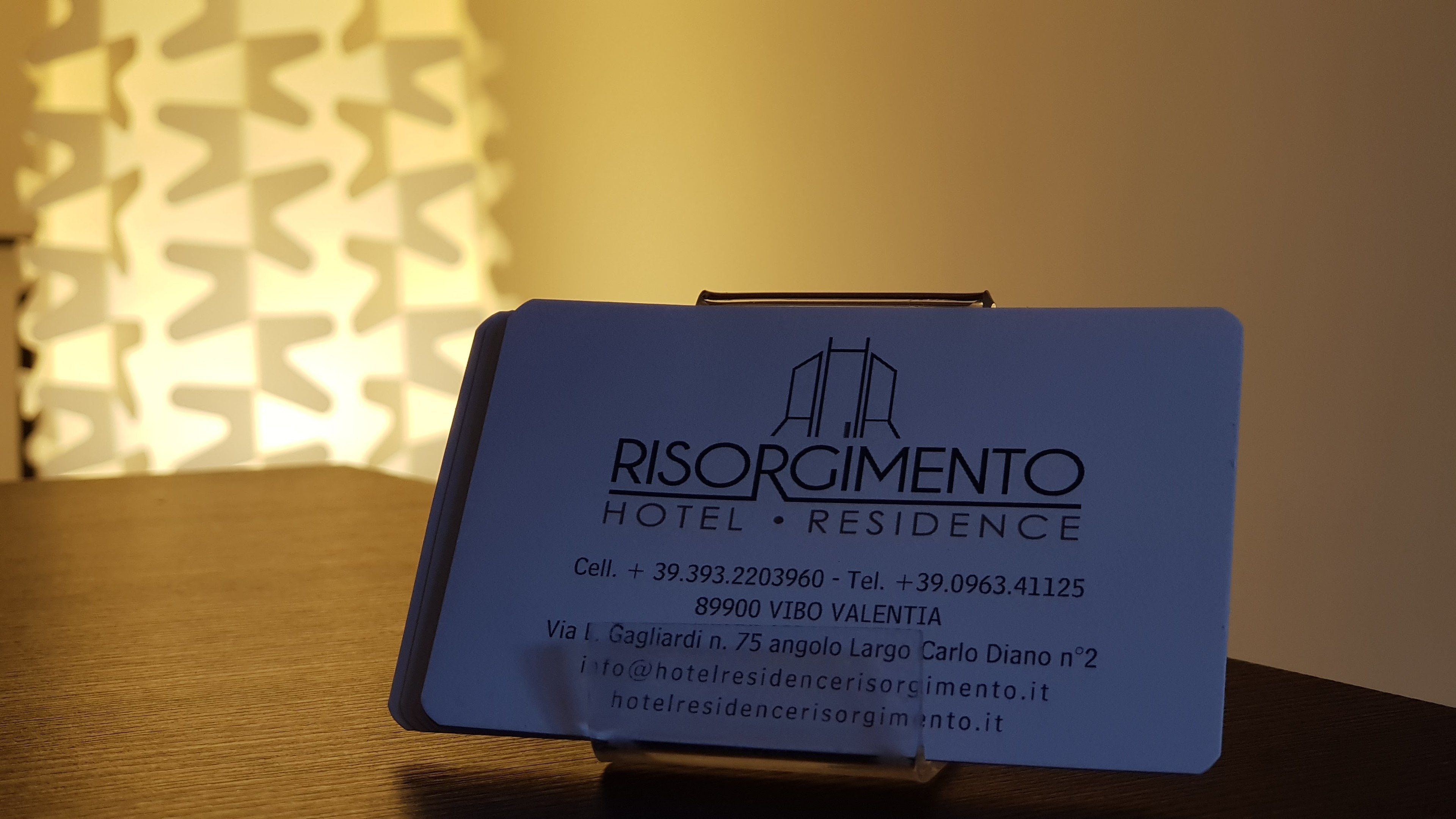 A business card for Risorgimento Hotel & Residence with contact details and address.