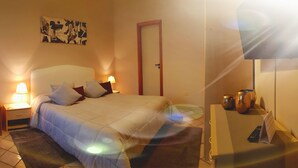 A hotel room with a bed, two bedside tables with lamps, a door, and a wall-mounted artwork. - Hotel Residence Risorgimento (Vibo Valentia)