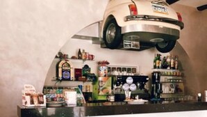 A coffee shop interior with a counter, a coffee cup on a saucer, and various items on shelves. - Hotel Residence Risorgimento (Vibo Valentia)