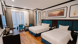 Quarto de hotel com duas camas, uma escrivaninha, uma cadeira, uma televisão e uma janela com cortinas.