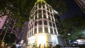Um hotel de vários andares com uma entrada notável, rodeado por edifícios altos e árvores.