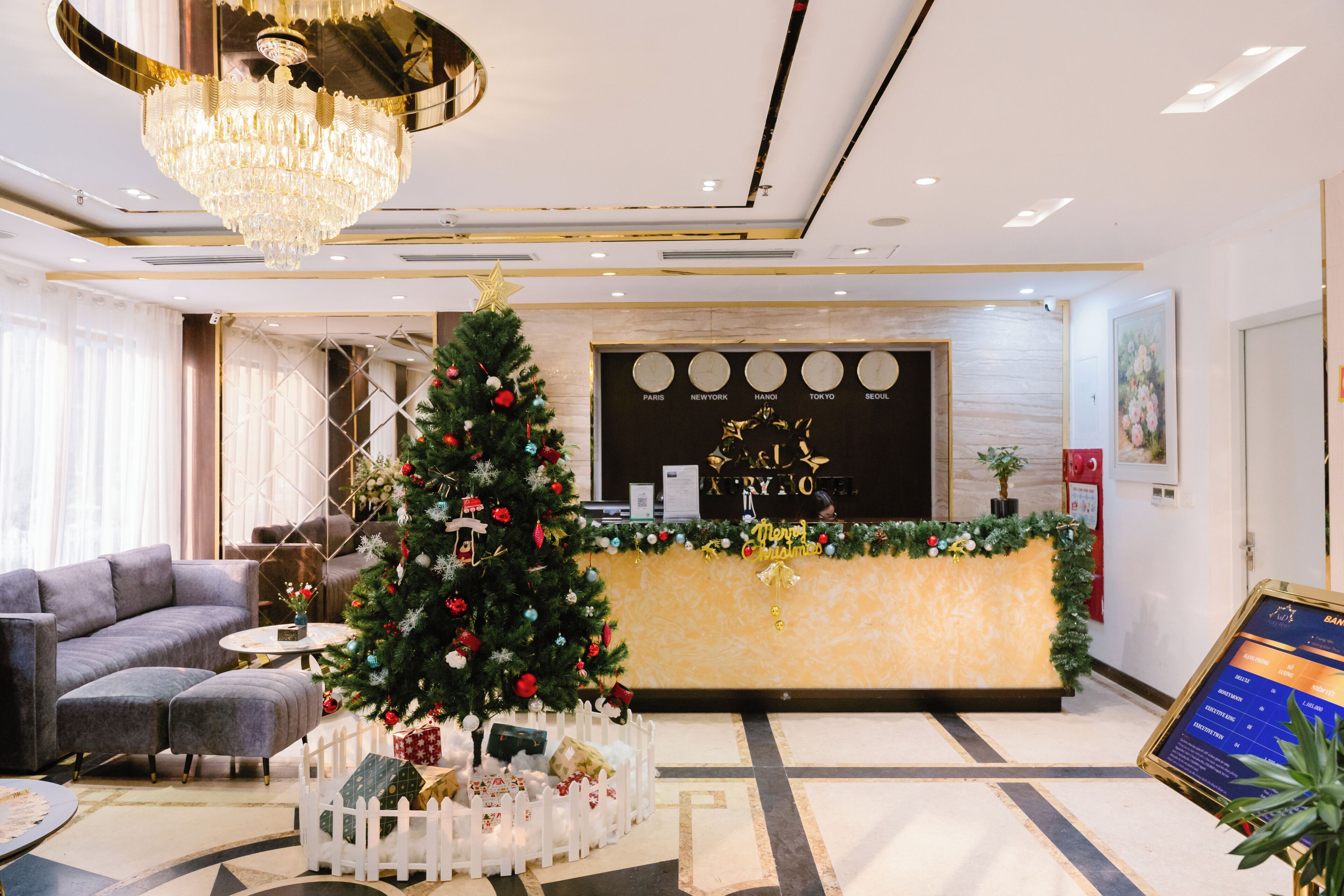 A hotel lobby with a Christmas tree, a reception desk, and a seating area.