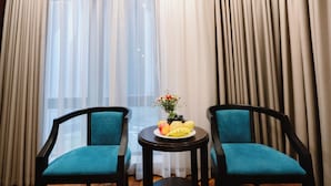 Quarto com duas cadeiras e uma mesinha com uma fruteira e flores.