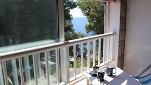 A balcony with a view of the sea, a white railing, and two mugs on a table. - Apartmani Ančila (Smokvica)