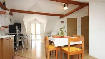 Uma área de refeições com mesa e cadeiras, teto com vigas de madeira e uma cozinha com fogão e armários.