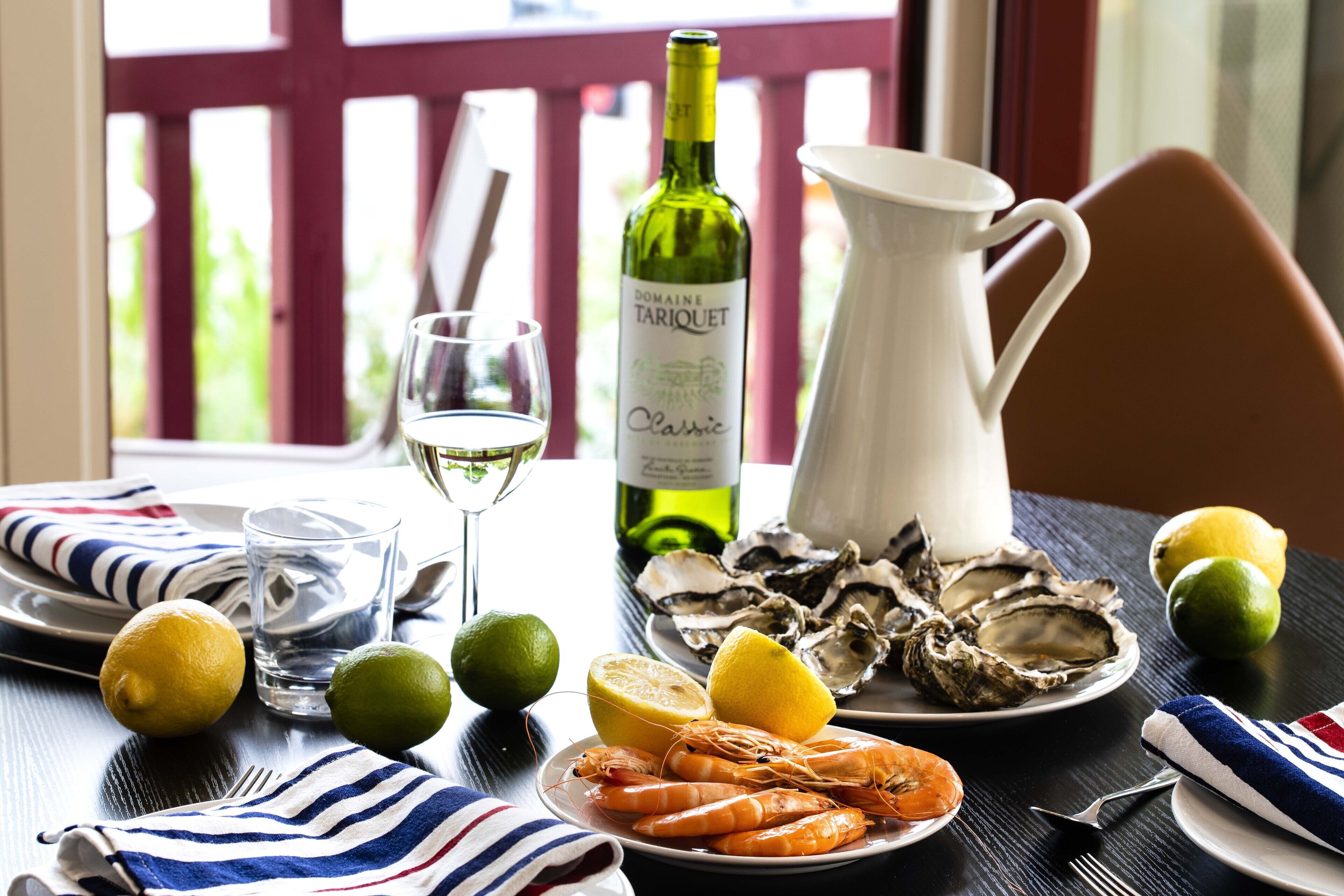 Una mesa de comedor con mariscos, una botella de vino y una jarrón.