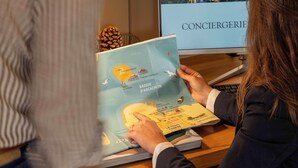 Une personne est assise à un bureau, un livre ouvert devant elle et une carte de Paris à proximité.