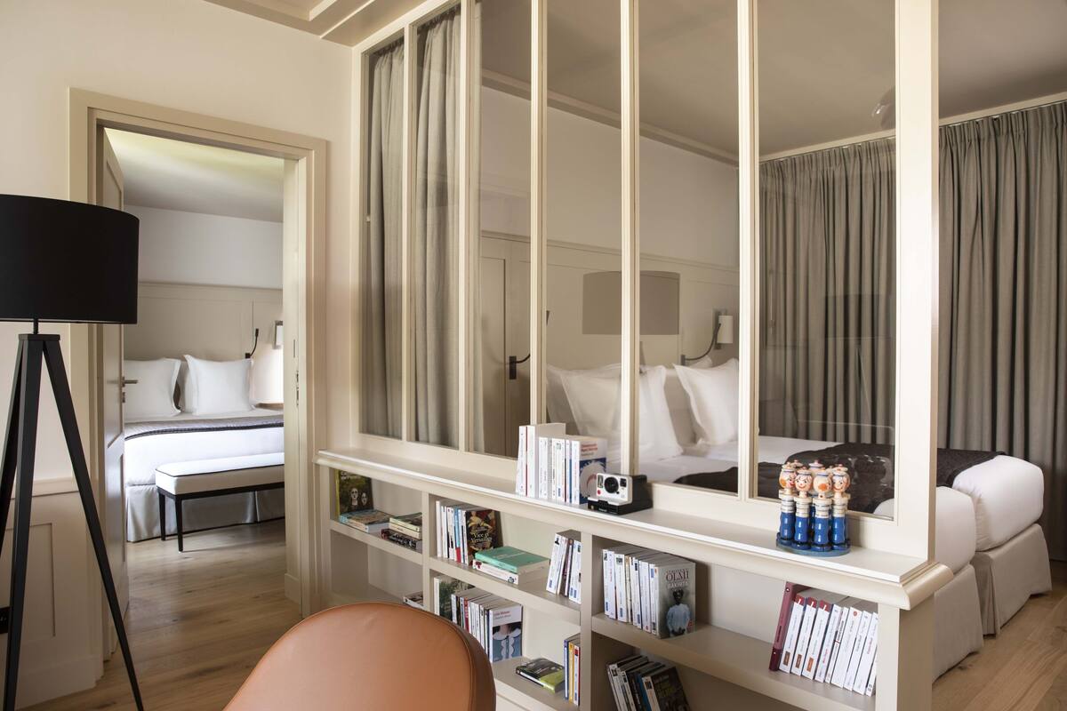 Ein Hotelzimmer mit einem großen Bett, einem Nachttisch, einem Bücherregal und einem Spiegel.