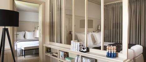 Una habitación de hotel con una cama grande, una mesita de noche, una estantería y un espejo.