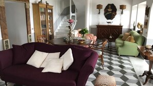 A living room with a purple sofa, a green armchair, a wooden cabinet, and a staircase. - Villa Cà Mea (La Spezia)