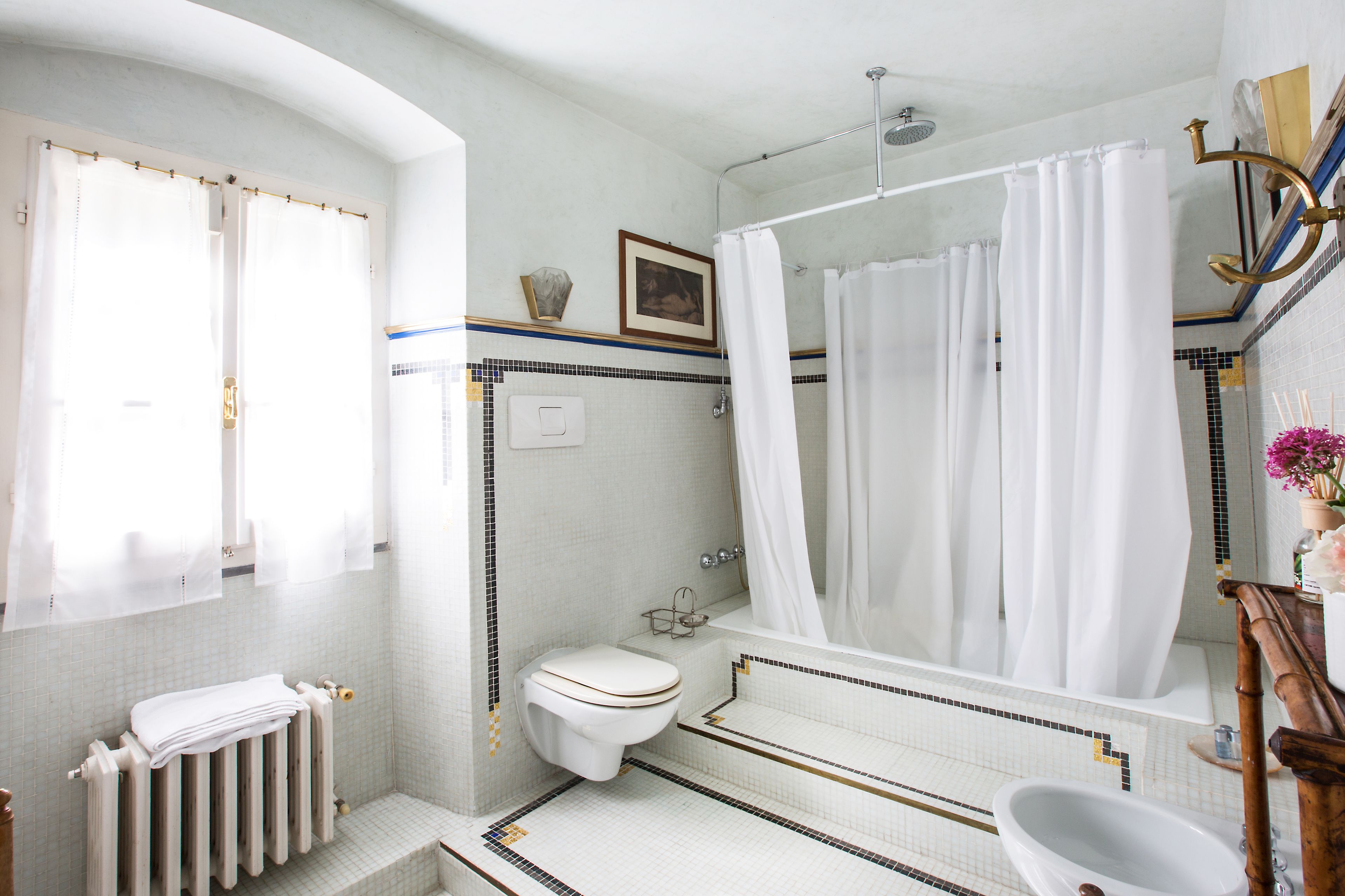 Une salle de bain équipée de toilettes, d’une baignoire, d’une douche et d’un grand miroir.