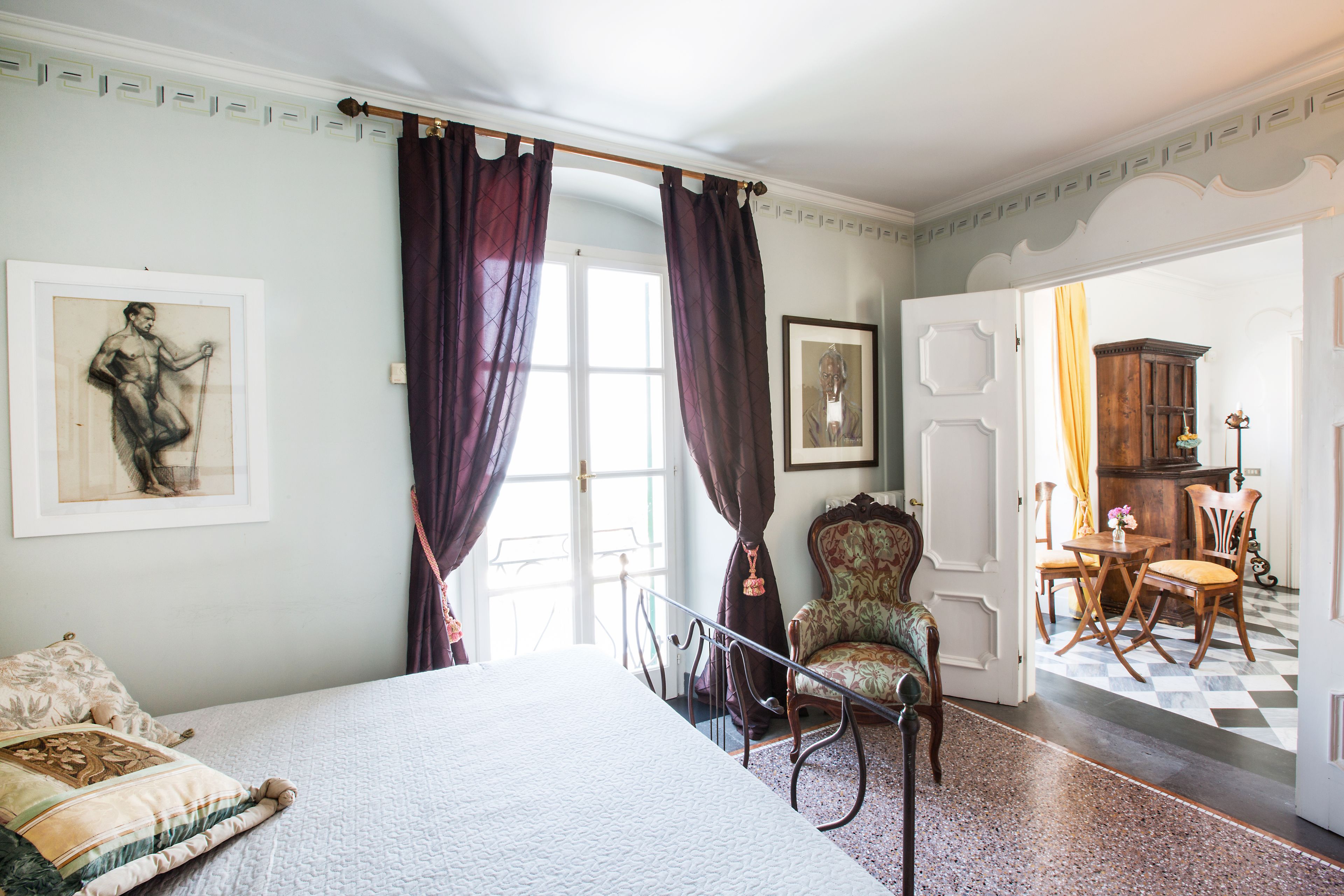 Een slaapkamer met een bed, een stoel, een bureau en een deur naar een andere kamer.