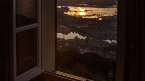 A view from a window at sunset, including a body of water, buildings, and a distant mountain range. - Villa Cà Mea (La Spezia)