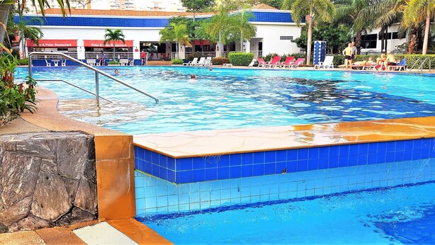 A swimming pool with a stone and tiled edge, surrounded by lounge chairs and a restaurant named "Peter & Peter Restaurant" in the background. - View Talay 2 - 1 bed Jomtien (Pattaya)