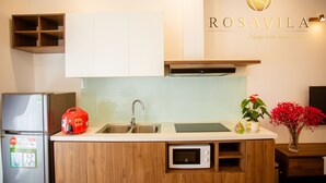 A modern kitchen with a built-in microwave, a stainless steel sink, and wooden cabinets. - Rosavila (Phan Dinh Phung)