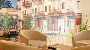 A hotel lobby with a large mural of a street scene, comfortable seating, and a table with a vase and bottles. - Rosavila (Phan Dinh Phung)