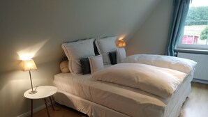 A bedroom with a bed, pillows, a bedside table, and a lamp. - Ferienapartments Lüneburger Heide - Rehlingen (Rehlingen)
