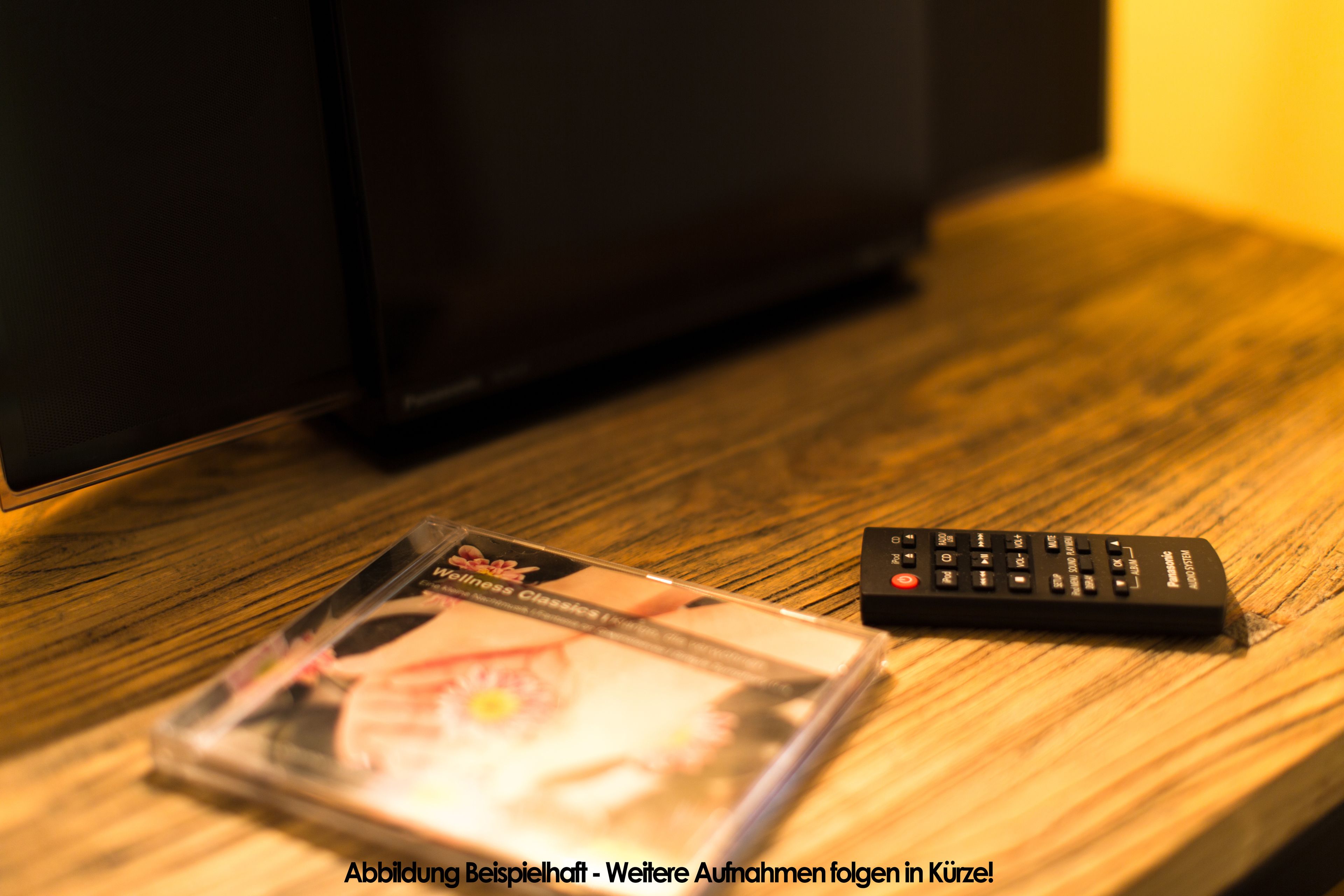 A CD and a remote control on a wooden surface.
