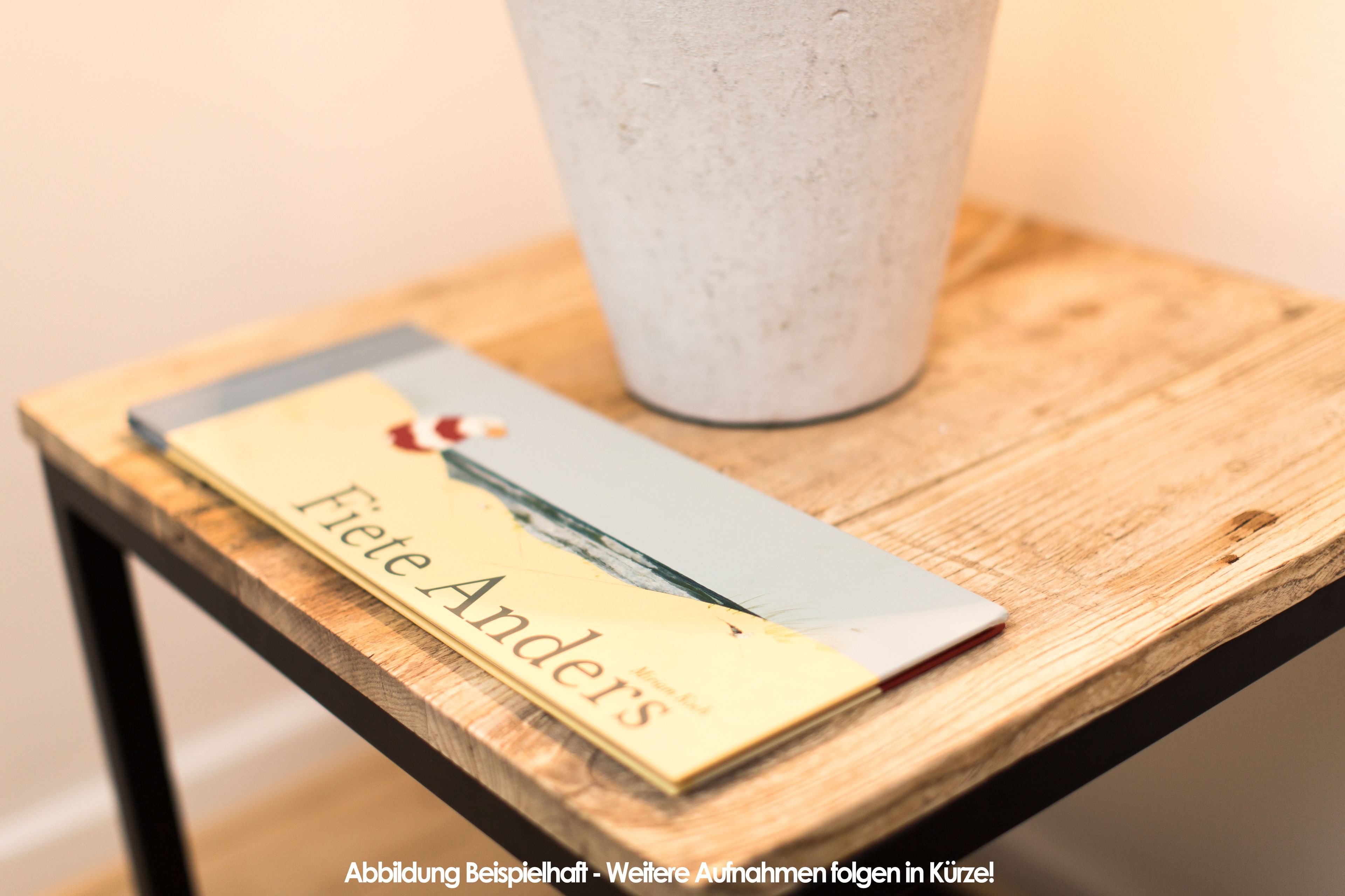 A book titled 'Fiete Anders' on a wooden table with a textured white object beside it.