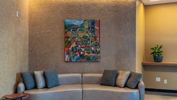 Una sala de estar moderna con un sofá gris curvo, una mesa de centro redonda de madera y un cuadro abstracto colorido en la pared.