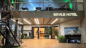 Exterior del Hotel Beville con un diseño moderno, que presenta una entrada destacada, una escalera y un área exterior cubierta.