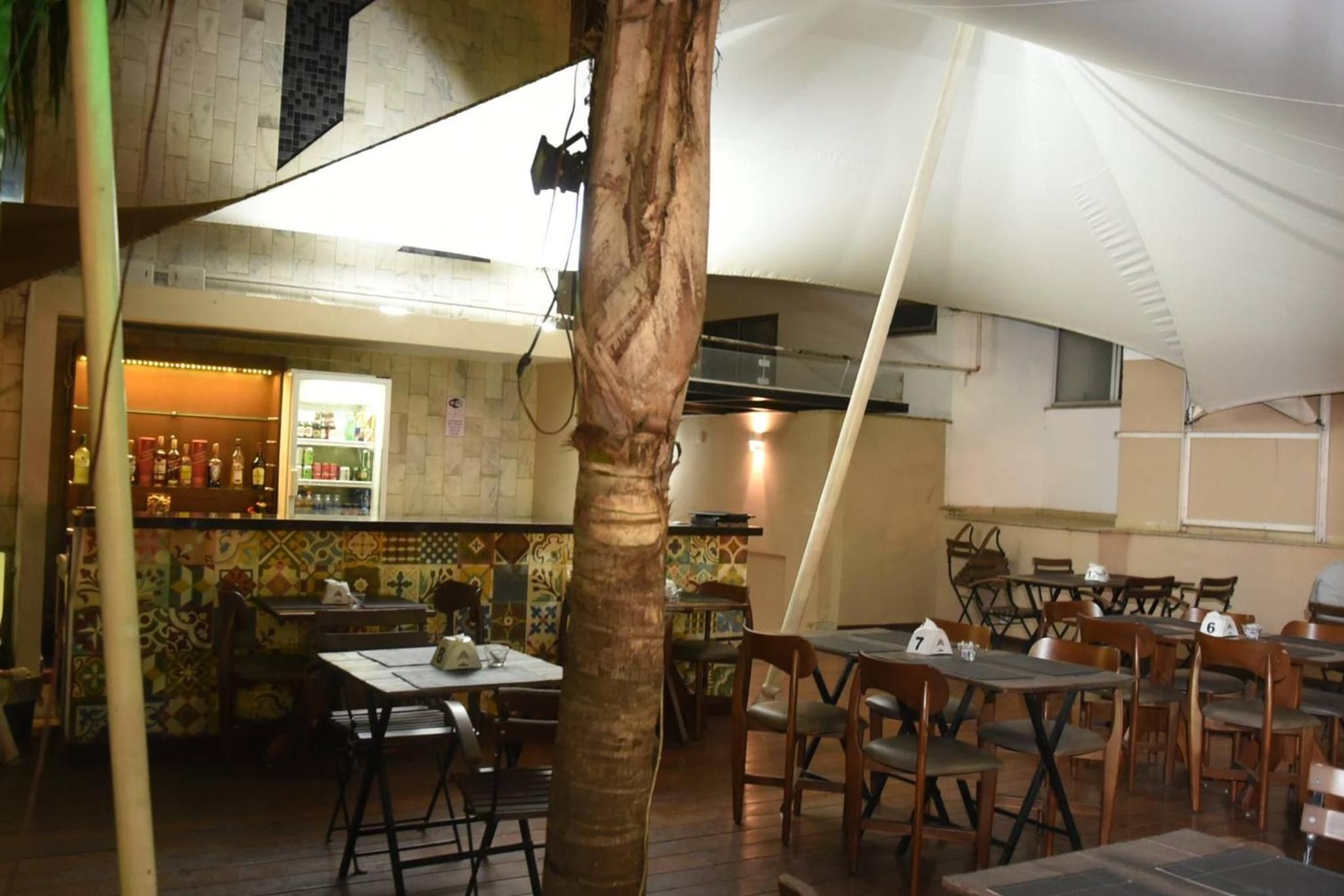 A restaurant with outdoor seating, a bar area, and a tiled wall.