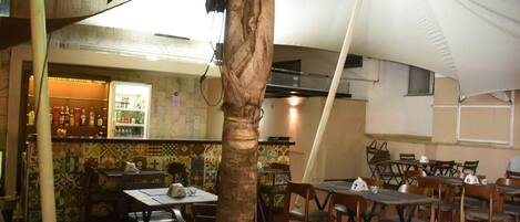 A restaurant with outdoor seating, a bar area, and a tiled wall.
