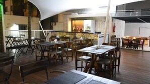 Un restaurante con mesas y sillas de madera, una zona de bar y un techo alto.