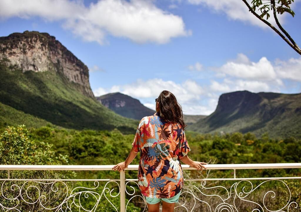 Una persona parada en un balcón con vista a un paisaje montañoso.