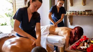 A massage therapy session in a room with wooden shelves and jars.