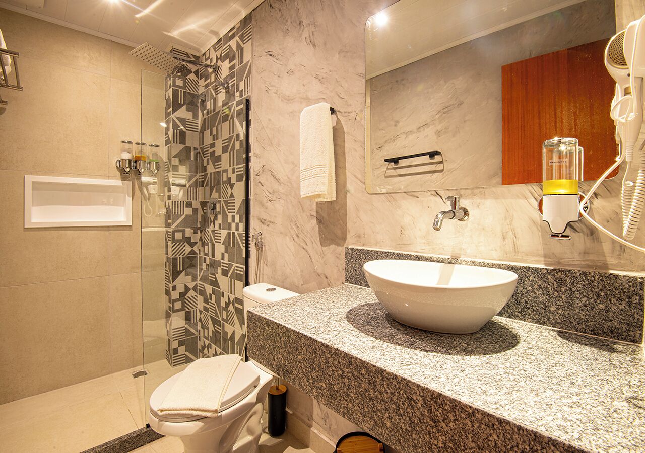 Une salle de bain moderne avec un grand lavabo, une cabine de douche en verre et un mur recouvert de carreaux de marbre.