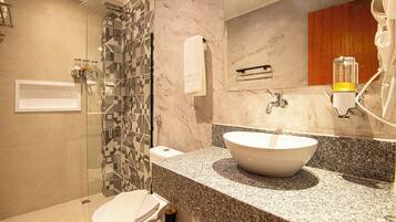 Une salle de bain moderne avec un grand lavabo, une cabine de douche en verre et un mur recouvert de carreaux de marbre.